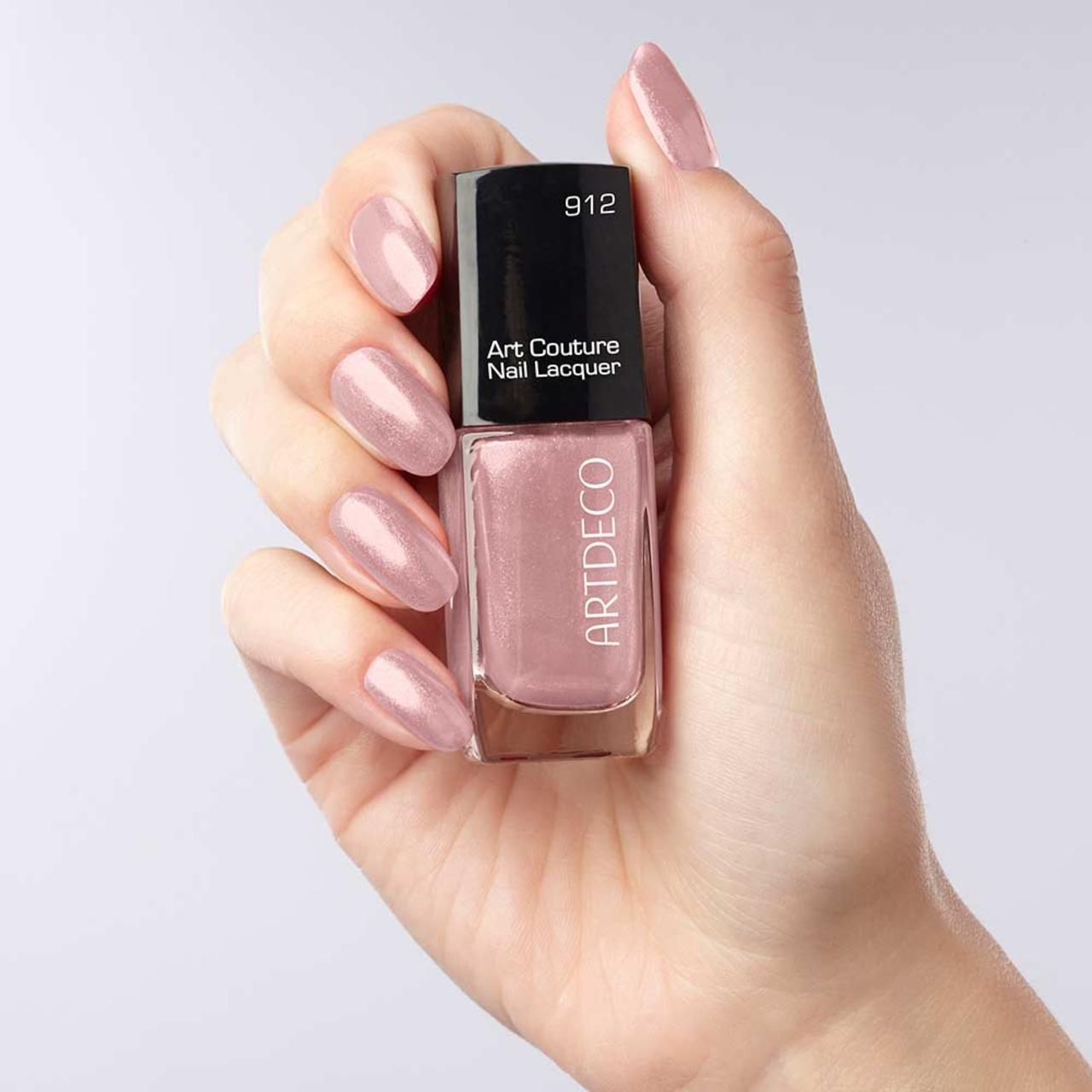 Mano che tiene un flacone di smalto per unghie. Artdeco Art Couture Nail Lacquer, tonalità 912. Unghie smaltate.