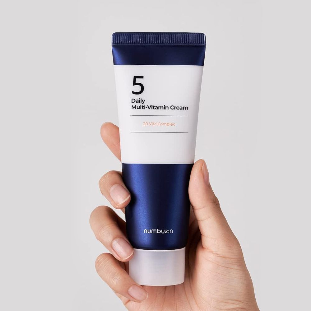 Tubo di crema in una mano. Scritta: 5, Daily Multi-Vitamin Cream, 20 Vita Complex. Marchio: numbuz:n.
