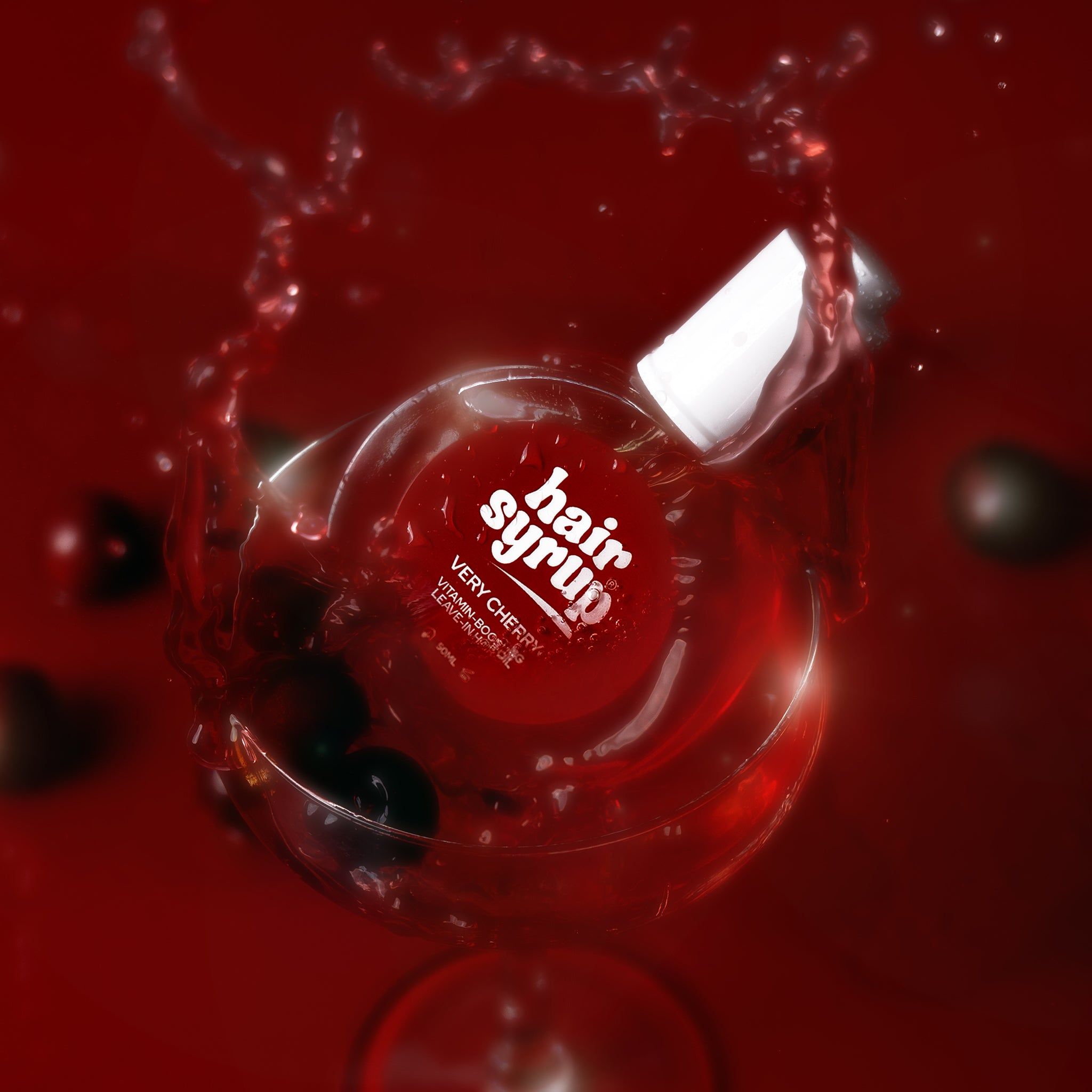 Flacone rotondo con liquido rosso, circondato da spruzzi. Tappo bianco, etichetta rossa.