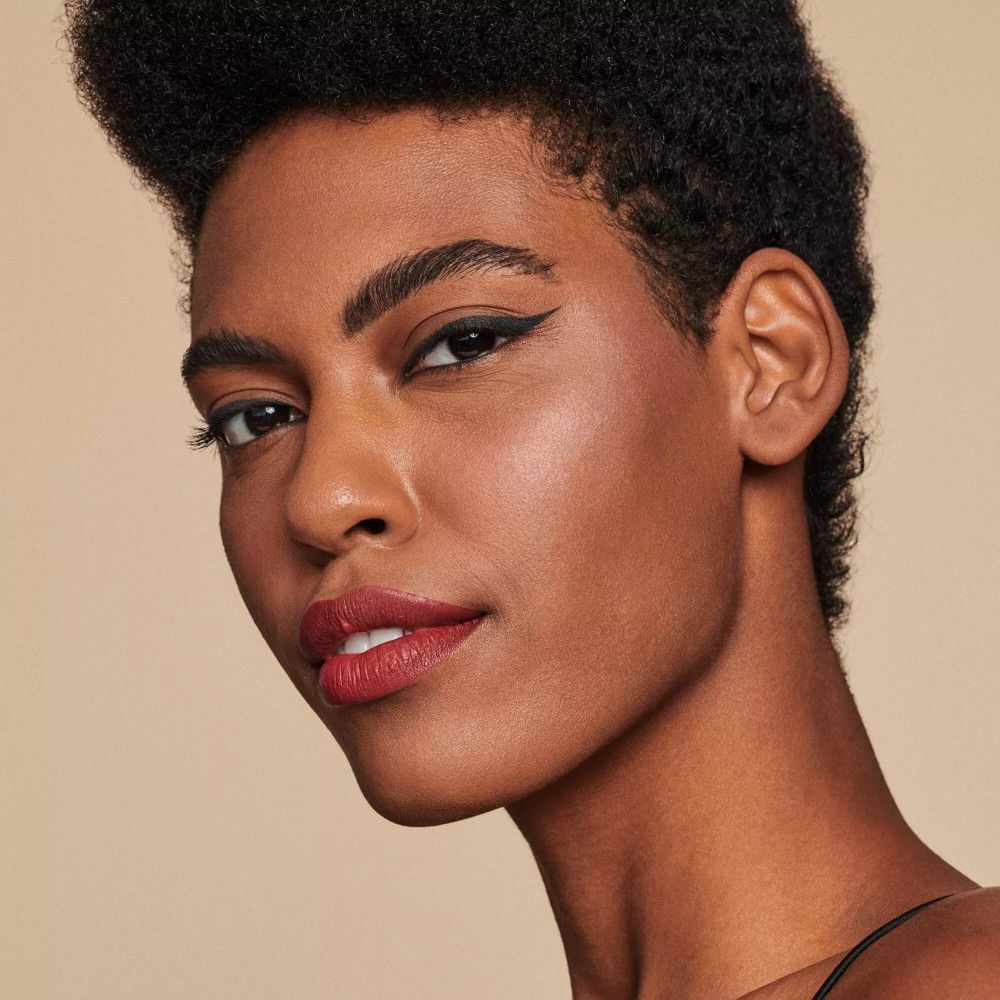 Ritratto di una donna con la pelle scura. Indossa eyeliner nero e rossetto rosso scuro.