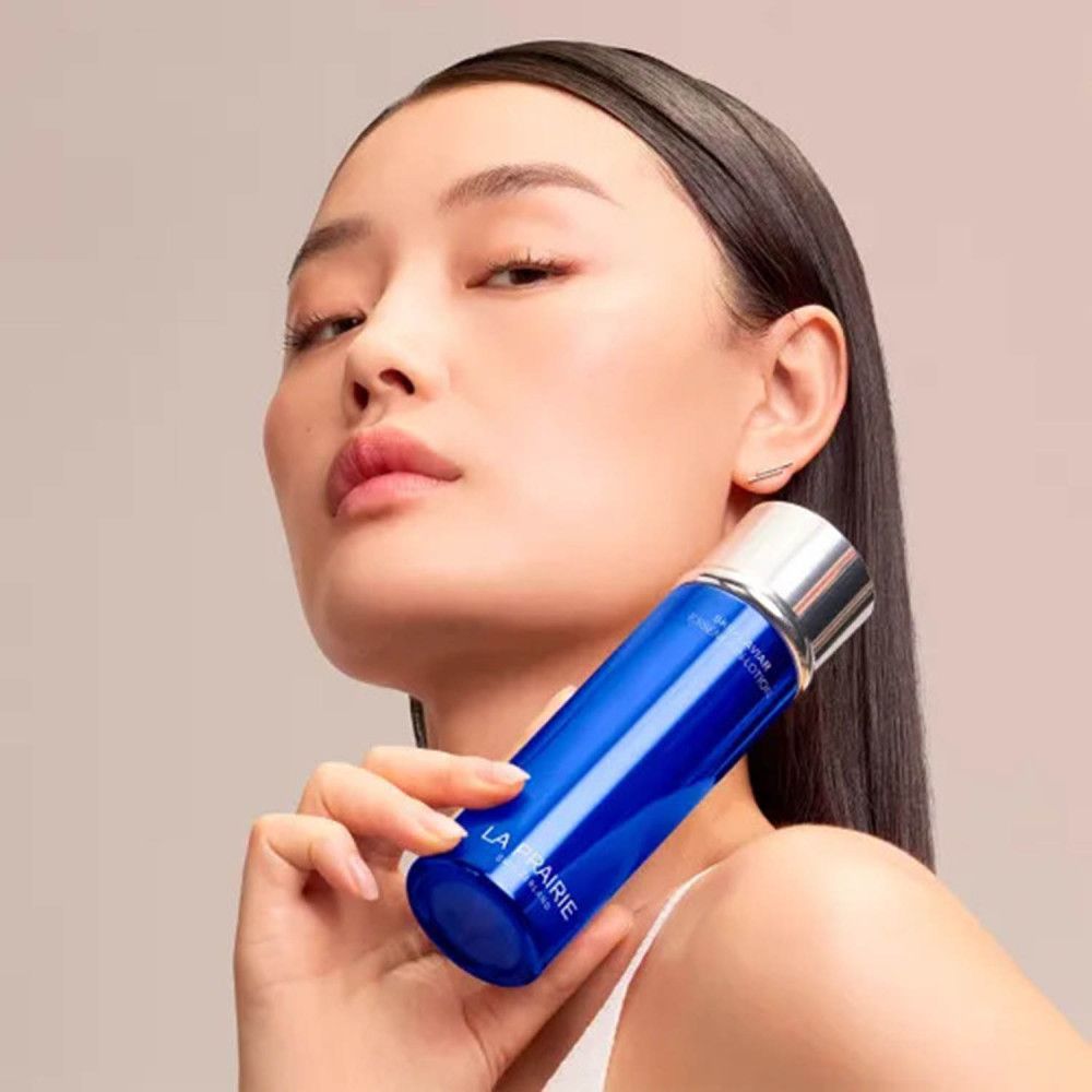 Donna che tiene un flacone La Prairie Skin Caviar Essence-in-Lotion.