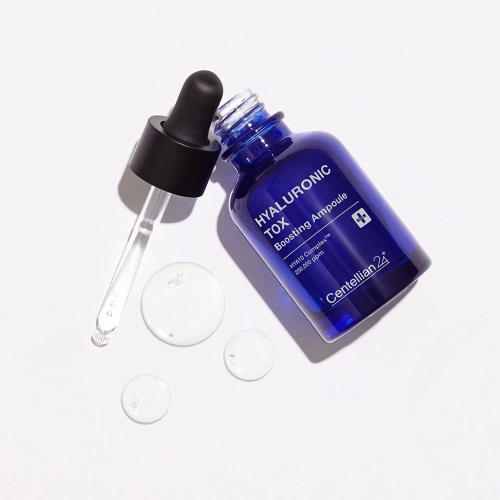 Flacone blu con contagocce e gocce di siero. Flacone sdraiato. Scritta: HYALURONIC TOX Boosting Ampoule. Marchio: Centellian 24.