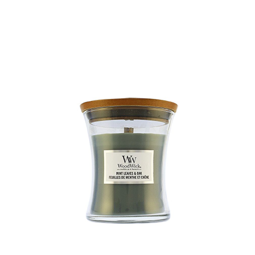 Candela verde a forma di clessidra con coperchio in legno. Etichetta con nome del prodotto e marchio WoodWick. Mint Leaves & Oak.