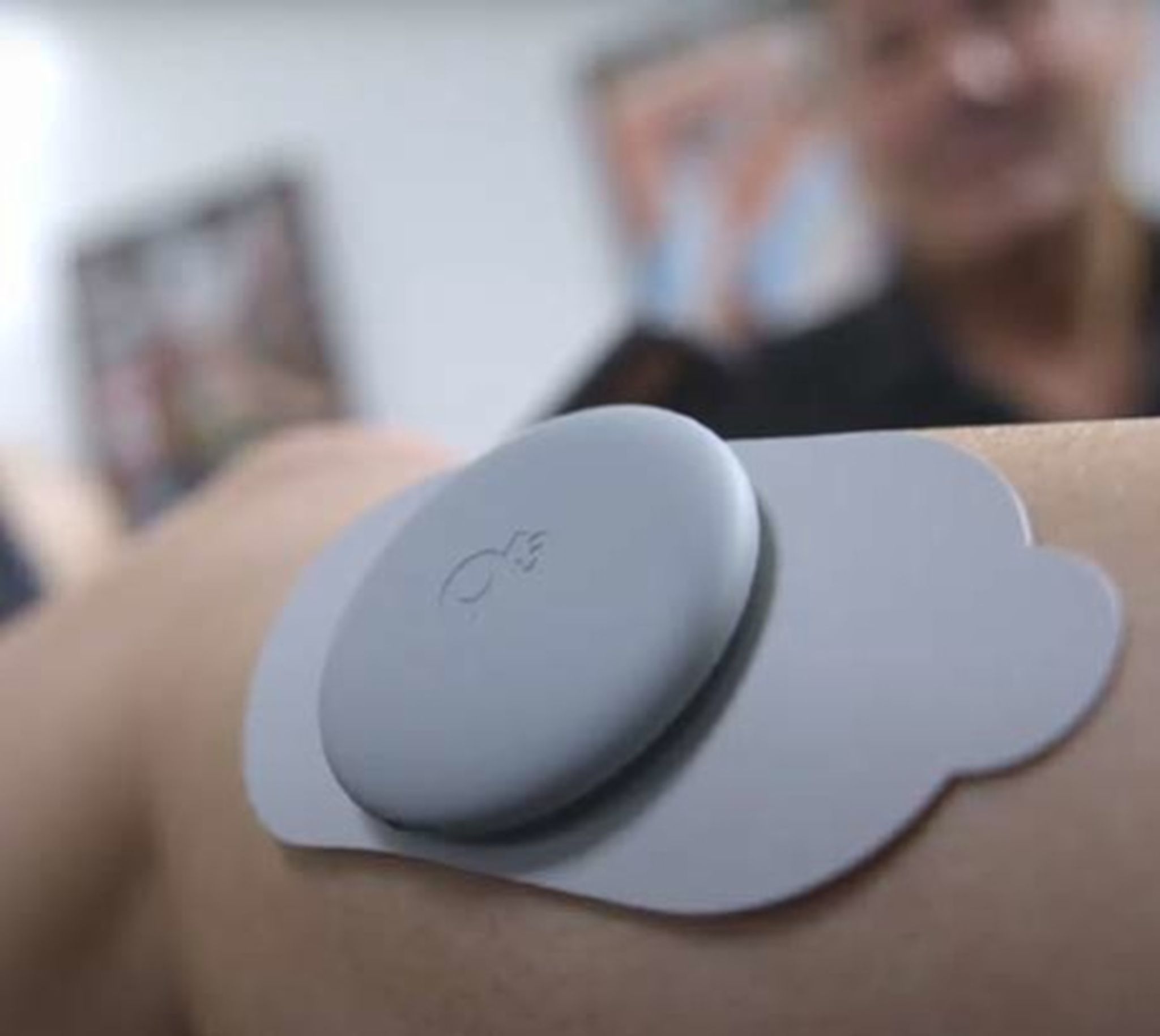 Uno stimolatore muscolare grigio su un pad, applicato sulla pelle.