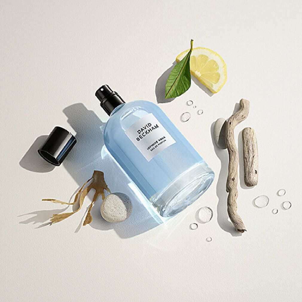Flacone in vetro con liquido blu, tappo nero. Testo: DAVID BECKHAM, INFINITE AQUA, Eau de Parfum. Decorazioni: limone, legno, alghe.