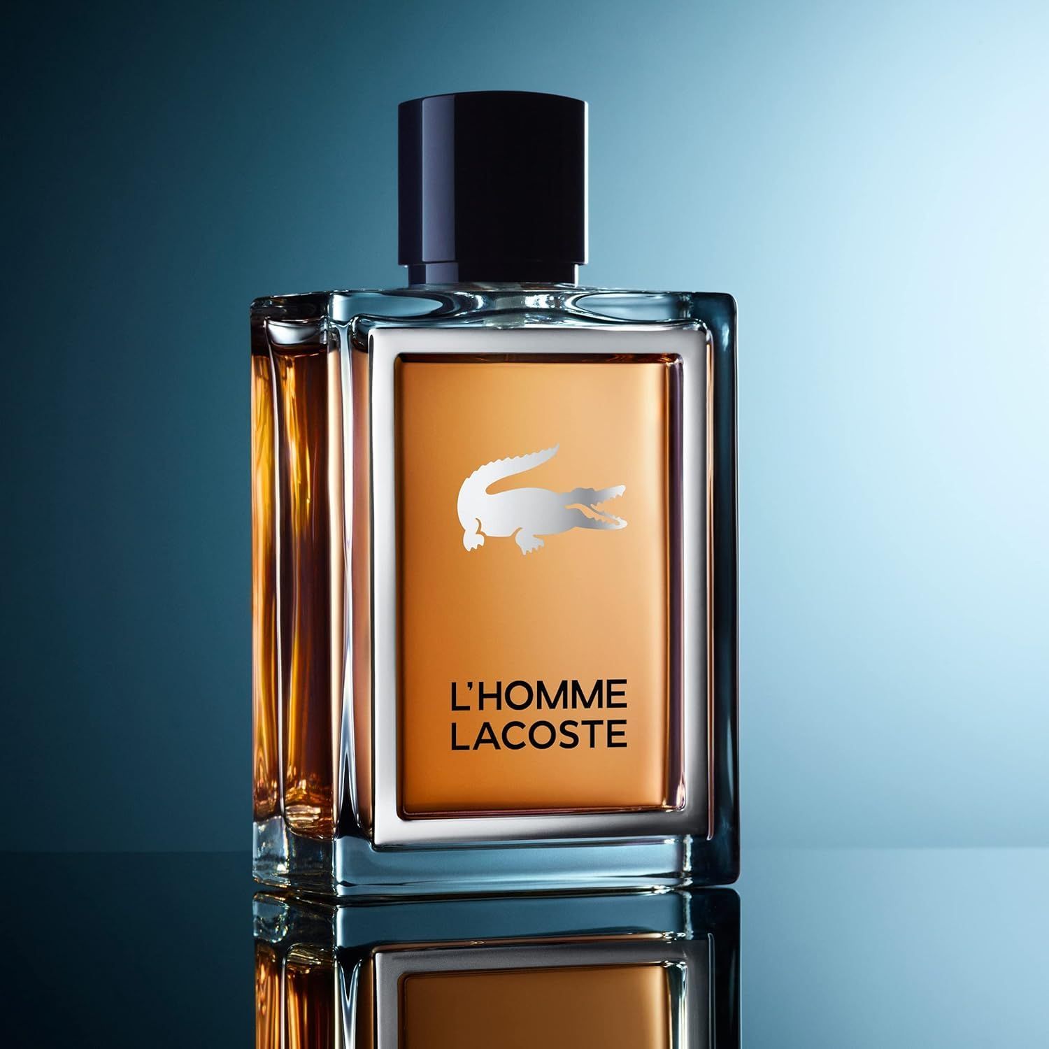 Flacone Lacoste L'Homme Eau de Toilette su superficie riflettente, sfondo blu.