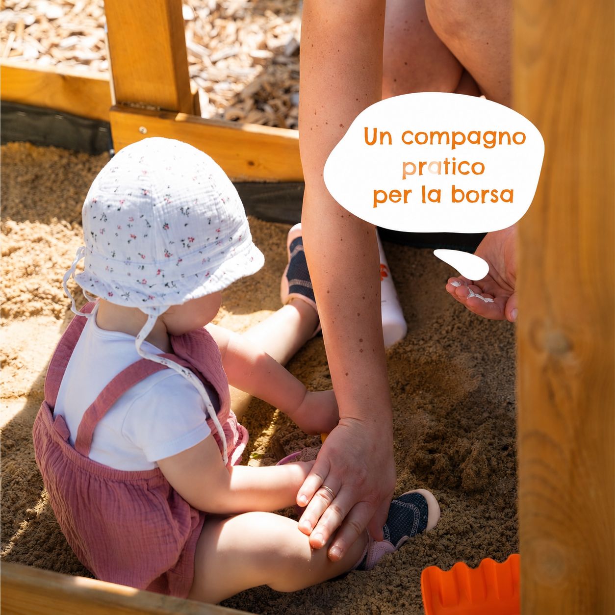 Un bambino seduto nella sabbia. Una mano tiene lo stick solare. Testo: Un compagno pratico per la borsa.