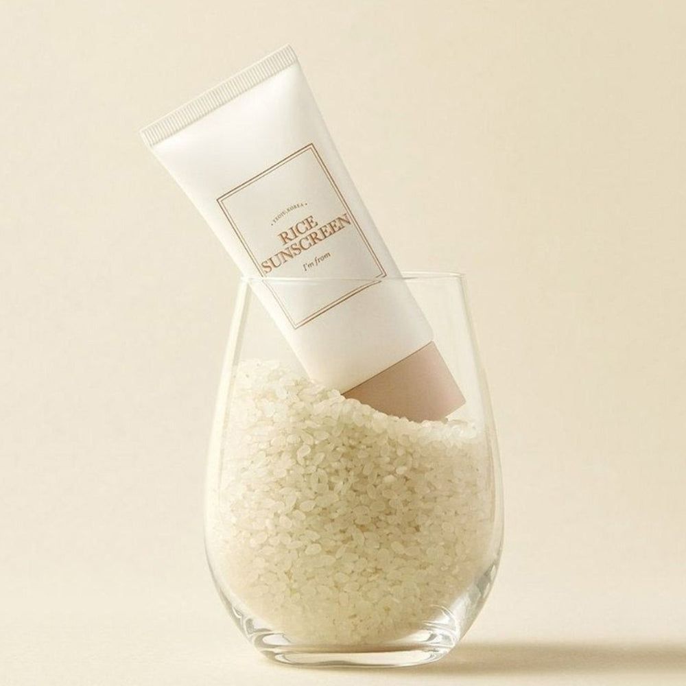 Tubo crema in vetro con riso. Scritta « Rice Sunscreen » e « I'm from ». Tappo beige.