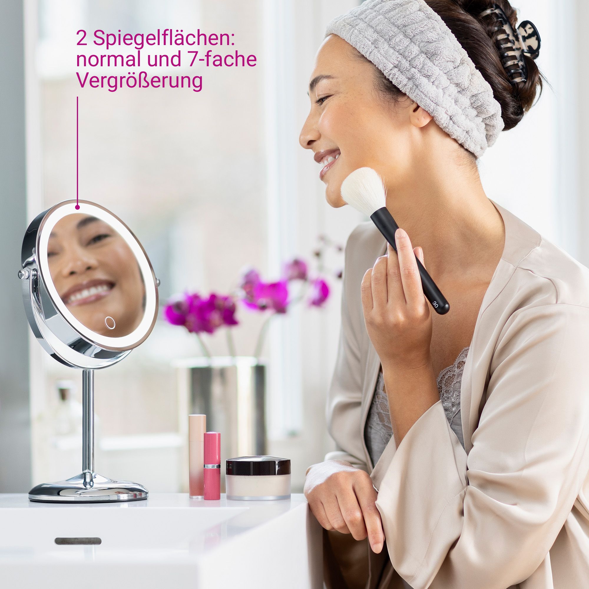 Donna si trucca con pennello davanti a specchio cosmetico illuminato (ingrandimento 7x).