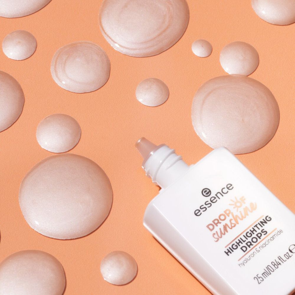 Flacone di prodotto e gocce su sfondo arancione. Scritta: essence, Drop of Sunshine, Highlighting Drops, Hyaluron & Niacinamide. 25 ml/0.84 fl. oz. e.