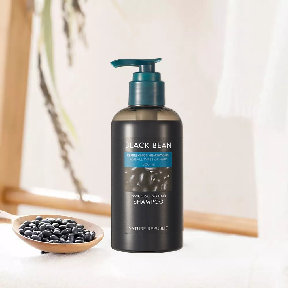 Flacone di shampoo nero con dosatore. Scritta: Black Bean, Invigorating Hair Shampoo. Fagioli neri in cucchiaio di legno.