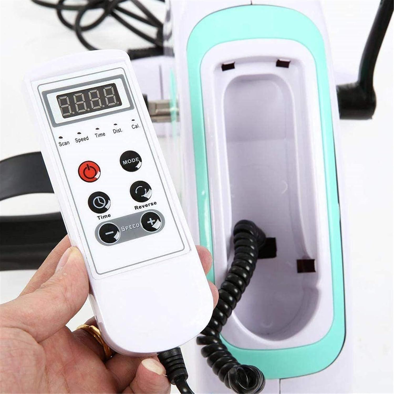 Primo piano del telecomando. Corpo bianco con pulsanti e display digitale. Cavo nero. Mano che tiene il telecomando.