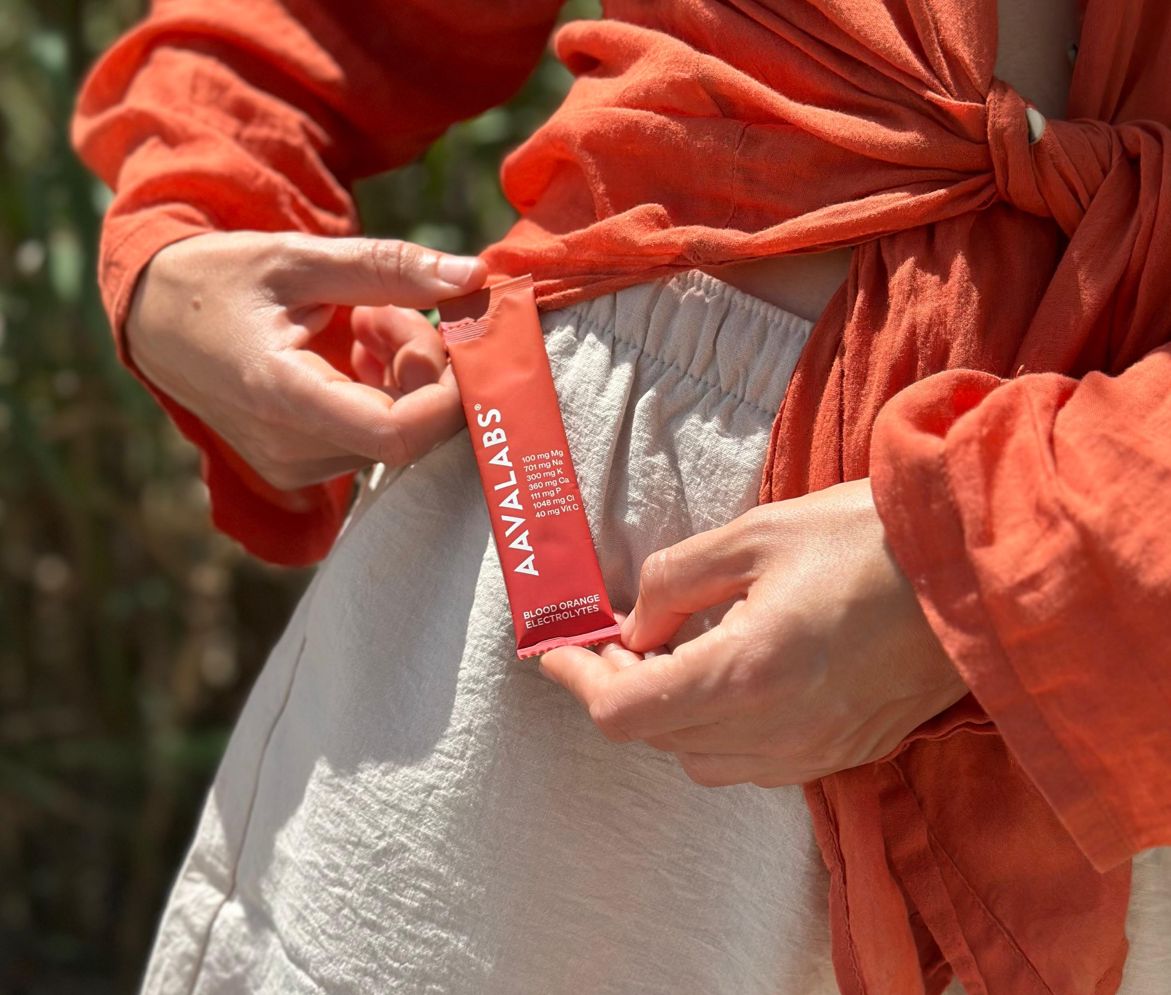 Stick di polvere di elettroliti AAVALABS tra le mani, arancia rossa.