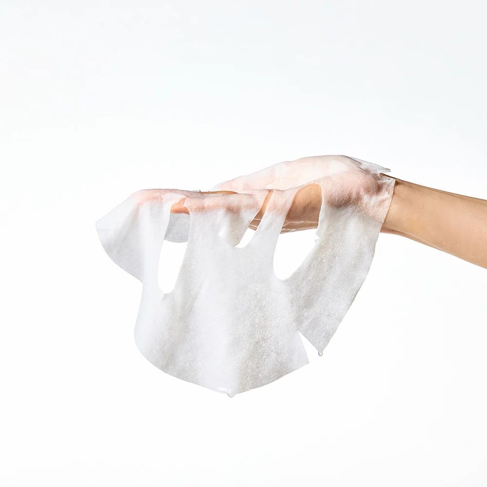 Mani che tengono una maschera facciale bianca. Aperture per occhi, naso e bocca. Sfondo bianco.