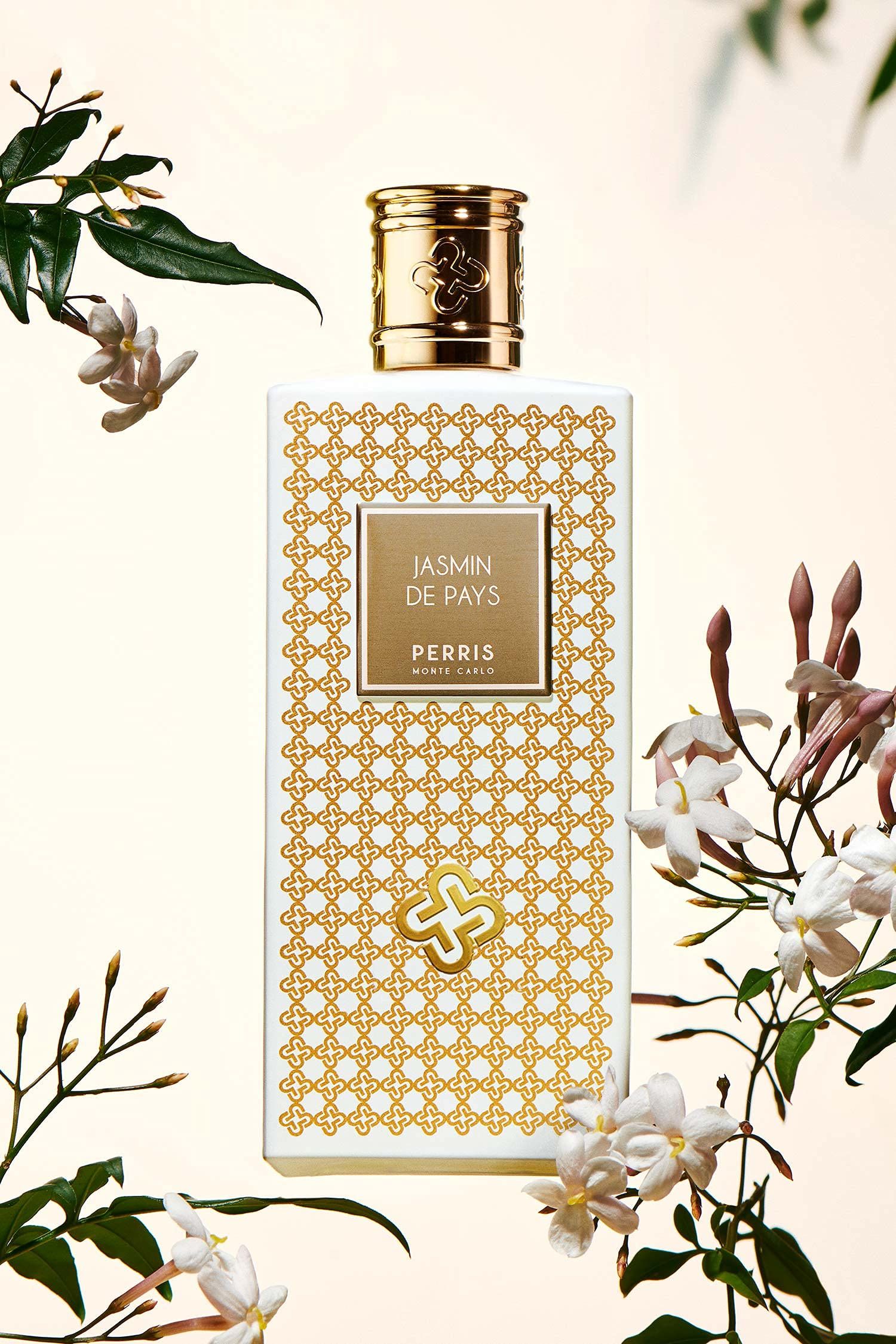 Flacone di profumo bianco e oro. Scritta: Jasmin de Pays, Perris Monte Carlo. Circondato da fiori di gelsomino.