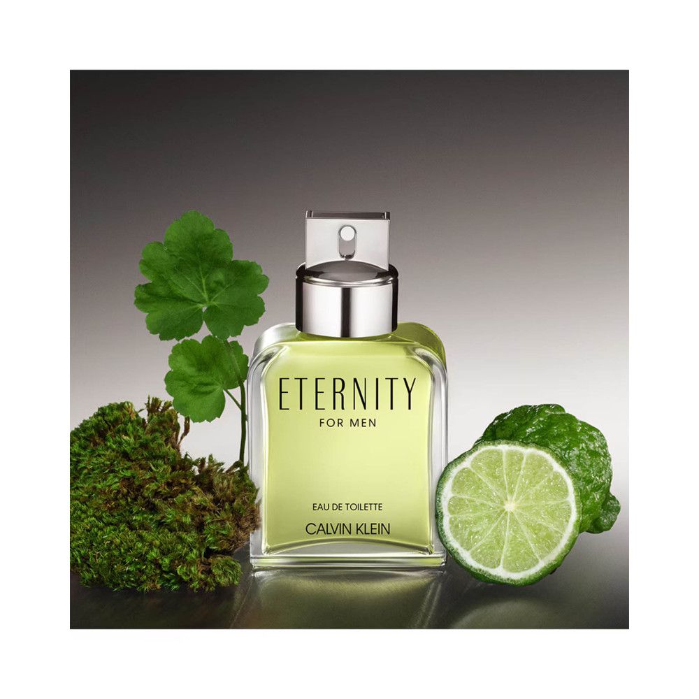 Flacone con tappo argentato, accanto a foglie verdi, muschio e una fetta di lime. Scritta: ETERNITY FOR MEN, Eau de Toilette, CALVIN KLEIN.