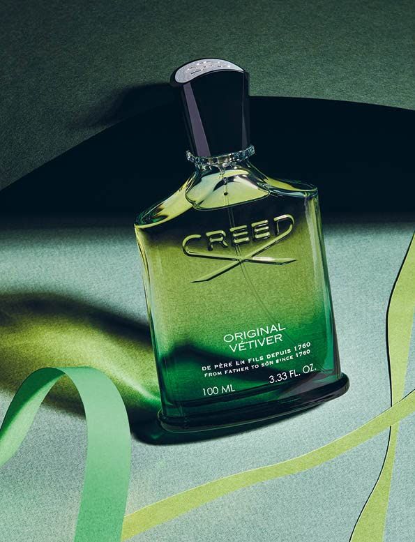 Flacone di profumo in vetro verde con tappo nero. Scritta: CREED ORIGINAL VETIVER. 100 ML. Su sfondo verde.