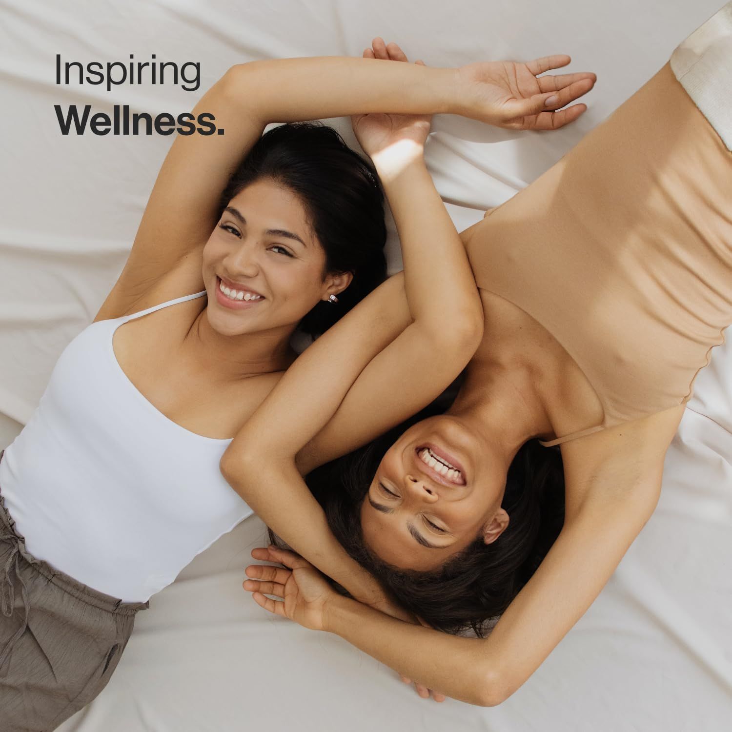 Due donne sdraiate sul letto. Testo: Inspiring Wellness.