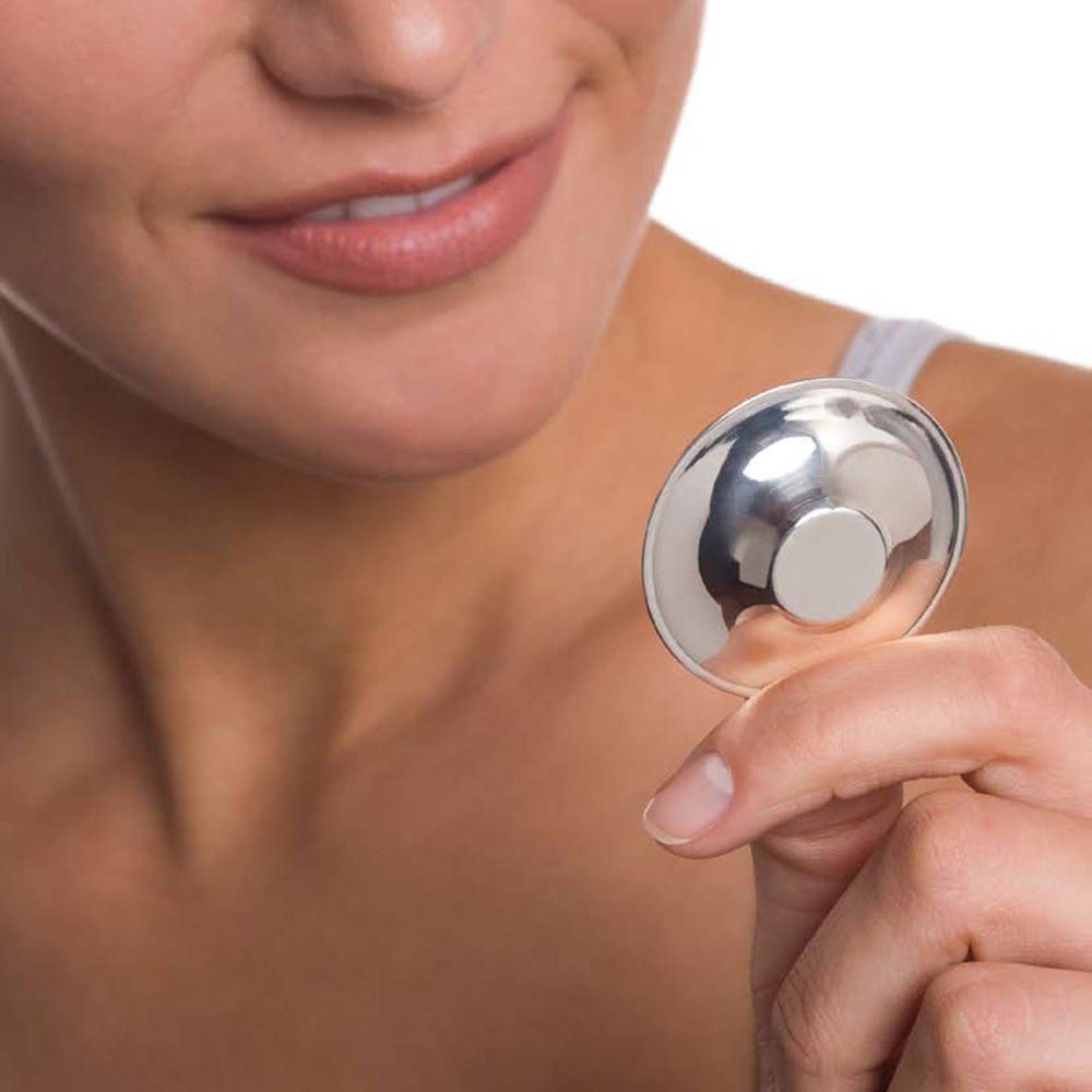 Protezione capezzolo argentata, tenuta da una persona. Forma rotonda con parte centrale rialzata.