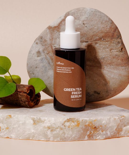 Flacone di vetro marrone con pipetta, posto su una pietra. ISNTREE Green Tea Fresh Serum. Sfondo: pietra e legno.