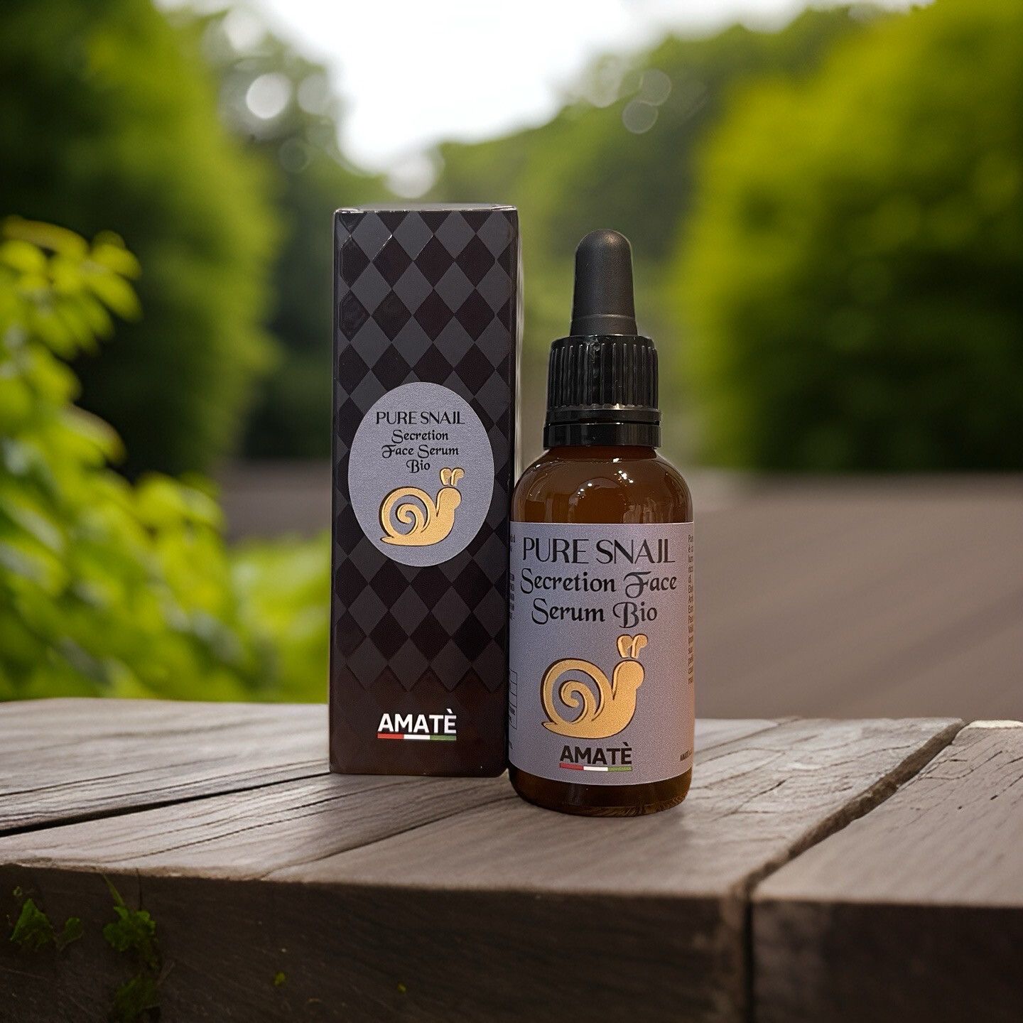 Flacone di vetro marrone con pipetta e scatola su legno. Scritta: Pure Snail Secretion Face Serum Bio. Logo: lumaca. Marchio: Amatè.
