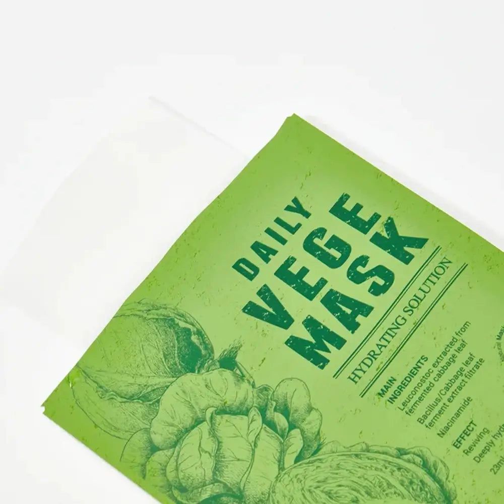 Maschera viso verde con scritta "DAILY VEGE MASK". Ingredienti principali e componenti stampati. Illustrazioni di verdure stampate.
