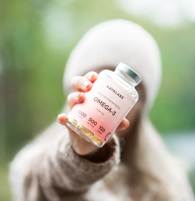 Persona che tiene una bottiglia di olio di pesce Omega-3 Aavalabs verso la telecamera.