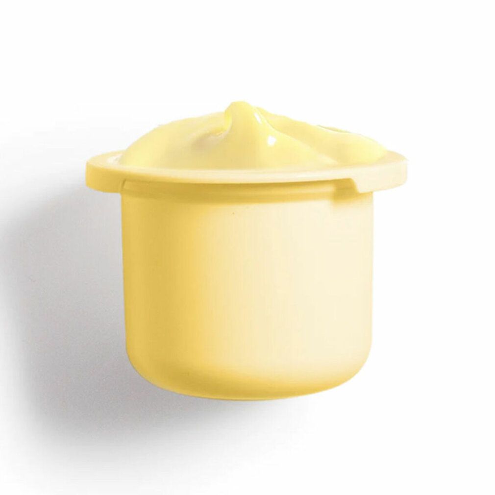 Crema giallastra in un piccolo contenitore rotondo. Il contenitore ha un bordo largo. La crema è bombata.