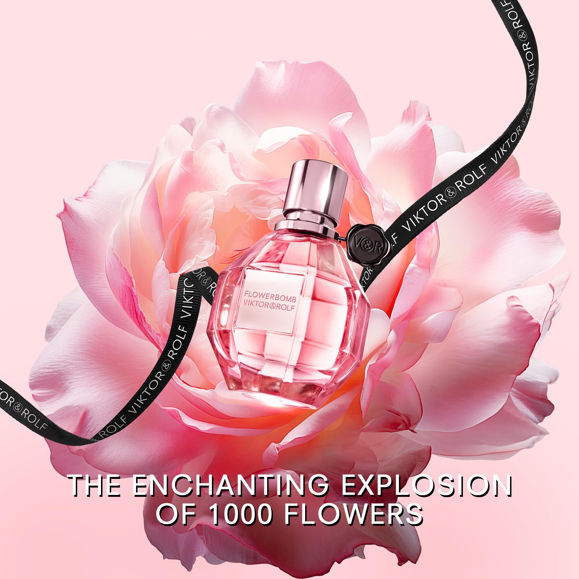 Flacone di profumo davanti a un fiore rosa. Nastro nero con logo. Testo: THE ENCHANTING EXPLOSION OF 1000 FLOWERS.