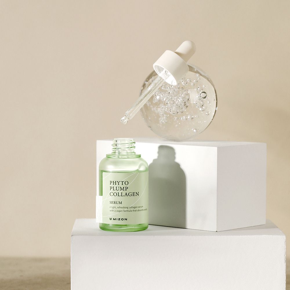 Flacone di siero e sfera di siero su piedistallo bianco. Nome del prodotto 'Phyto Plump Collagen' visibile.