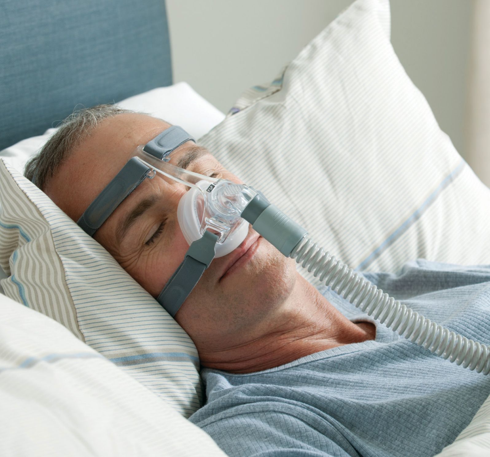 Uomo che dorme con maschera nasale e tubo collegati.