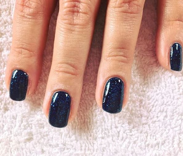 Primo piano di unghie smaltate di blu. Su un asciugamano bianco. Finitura lucida.