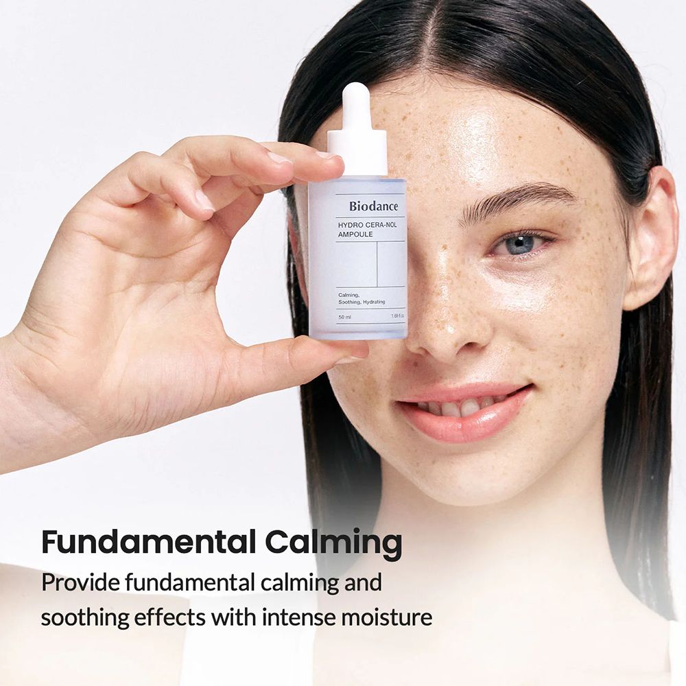 Donna che tiene un flacone davanti al viso. Scritta: Biodance, HYDRO CERA-NOL, AMPULE. Testo: Fundamental Calming. Ambiente luminoso.