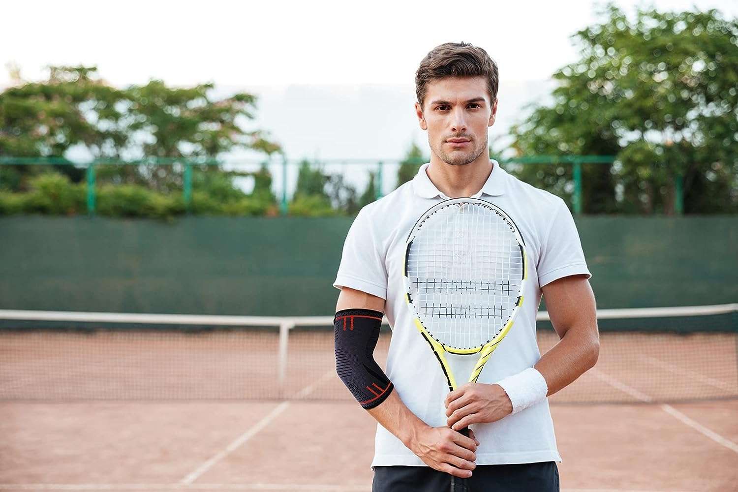 Uomo con racchetta da tennis su un campo. Indossa un tutore per il gomito.