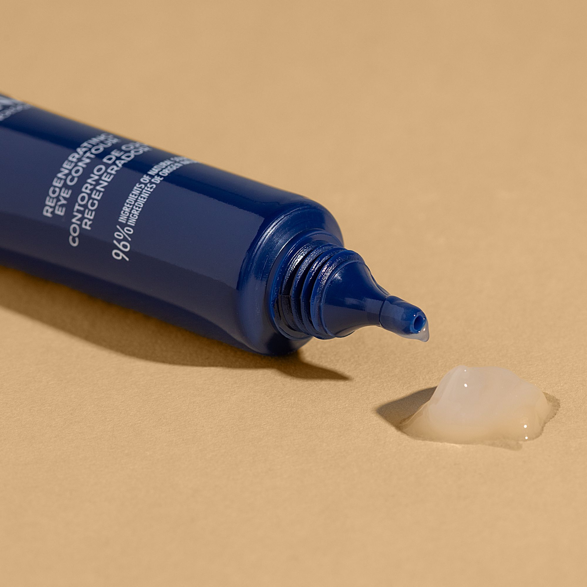 Tubo blu scuro, prodotto spremuto. Scritta: Regenerating Eye Contour. 96% ingredienti di origine naturale. Gel su sfondo beige.