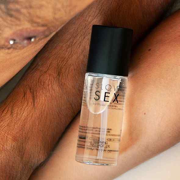 Flacone trasparente con tappo nero. Scritta: SLOW SEX. Scritta: Warming Massage Oil.