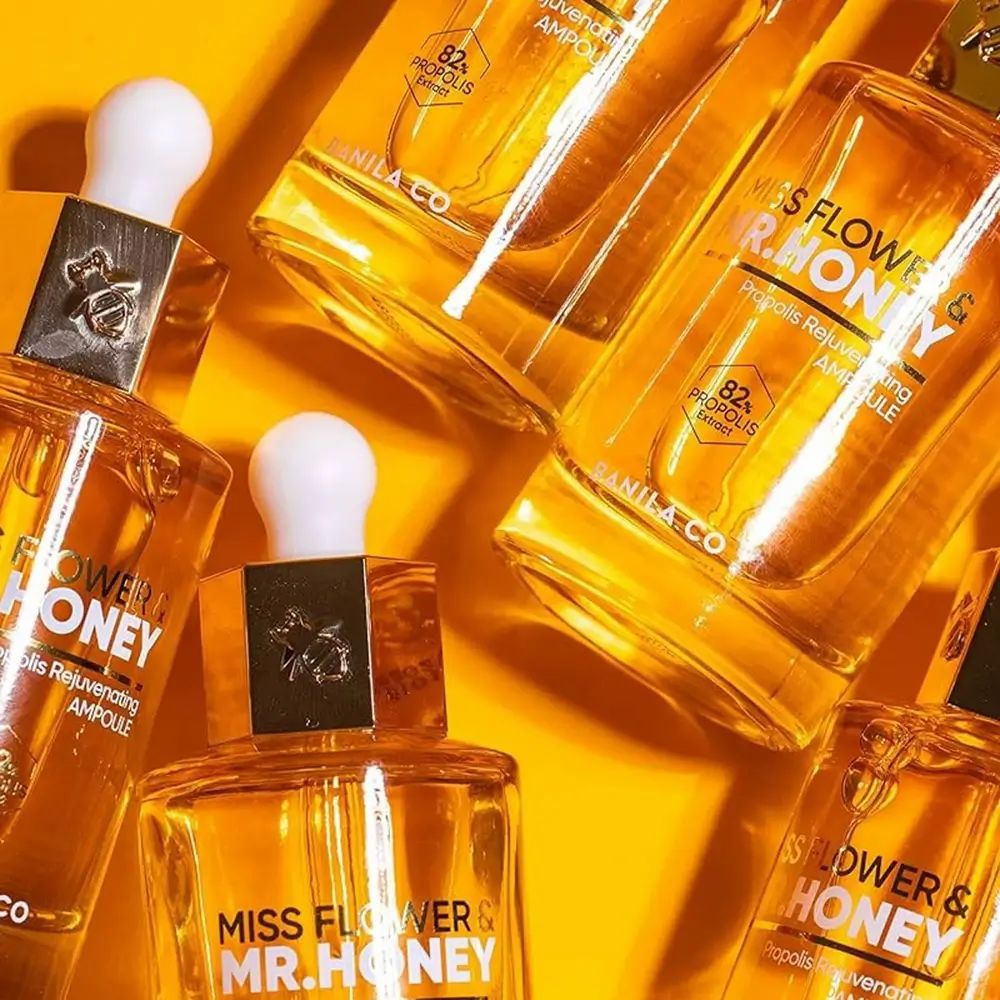 Diverse bottiglie di vetro con siero dorato. Scritta: Miss Flower & Mr. Honey. 82% Estratto di propoli.