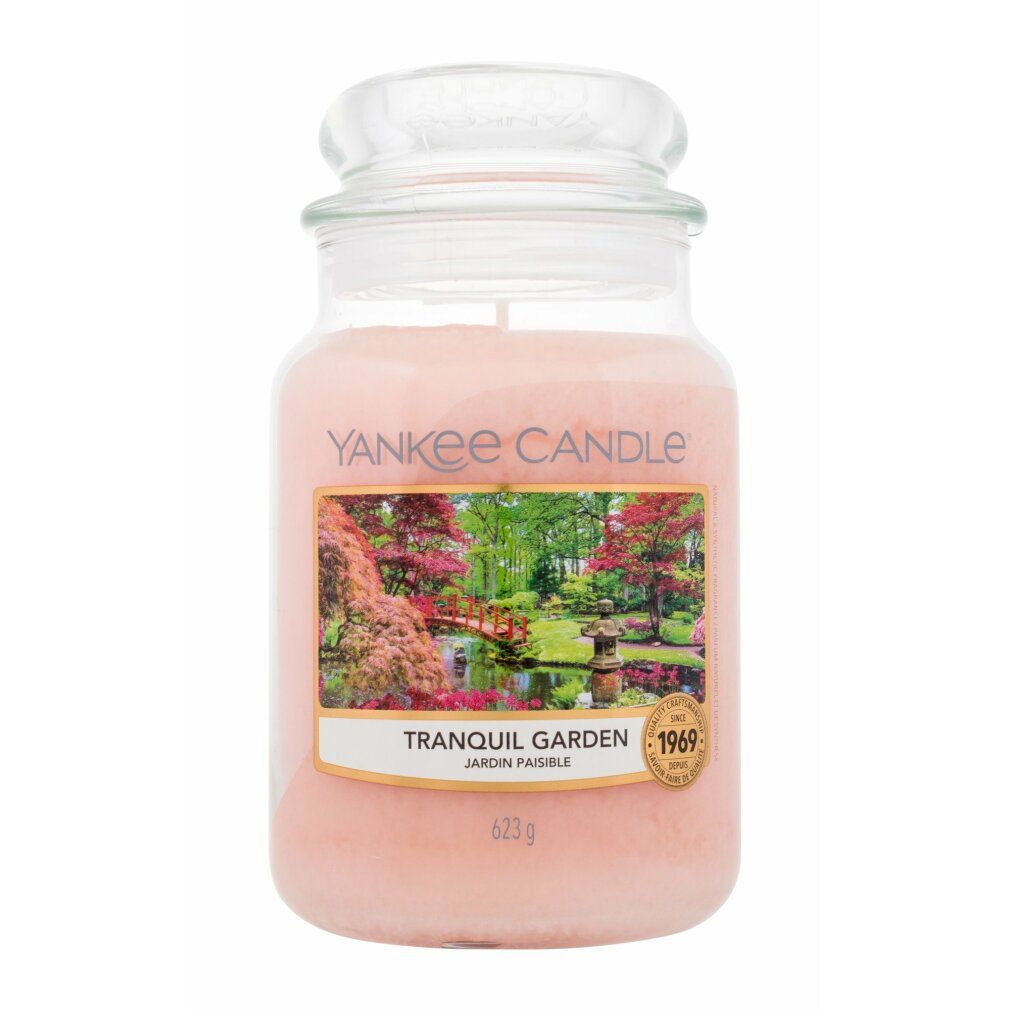 Candela profumata in vaso con coperchio. Etichetta con paesaggio e testo. Marchio: Yankee Candle. Scritta: Tranquil Garden, 623g.