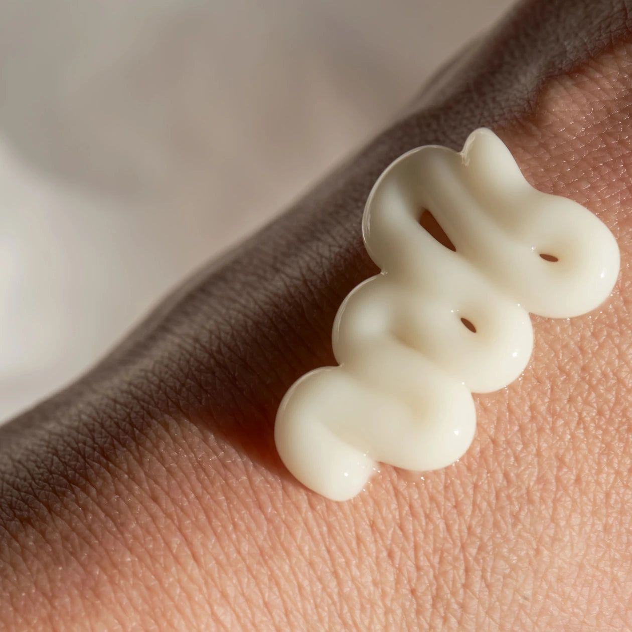 Primo piano di una crema bianca sulla pelle. La crema è applicata a forma di onda.