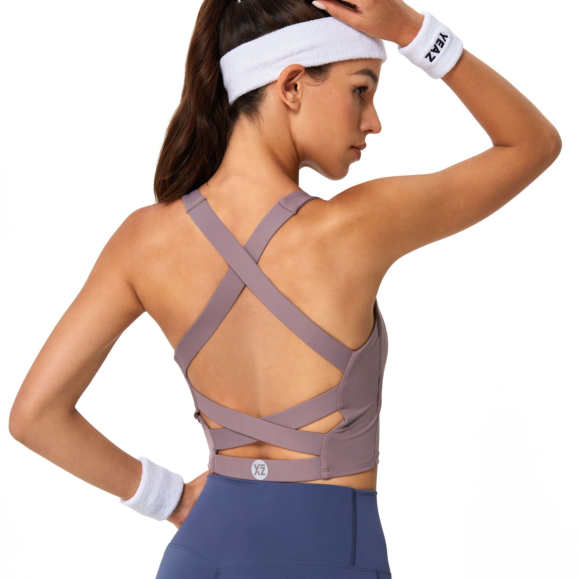 Reggiseno sportivo viola con spalline incrociate sulla schiena e fascia bianca.