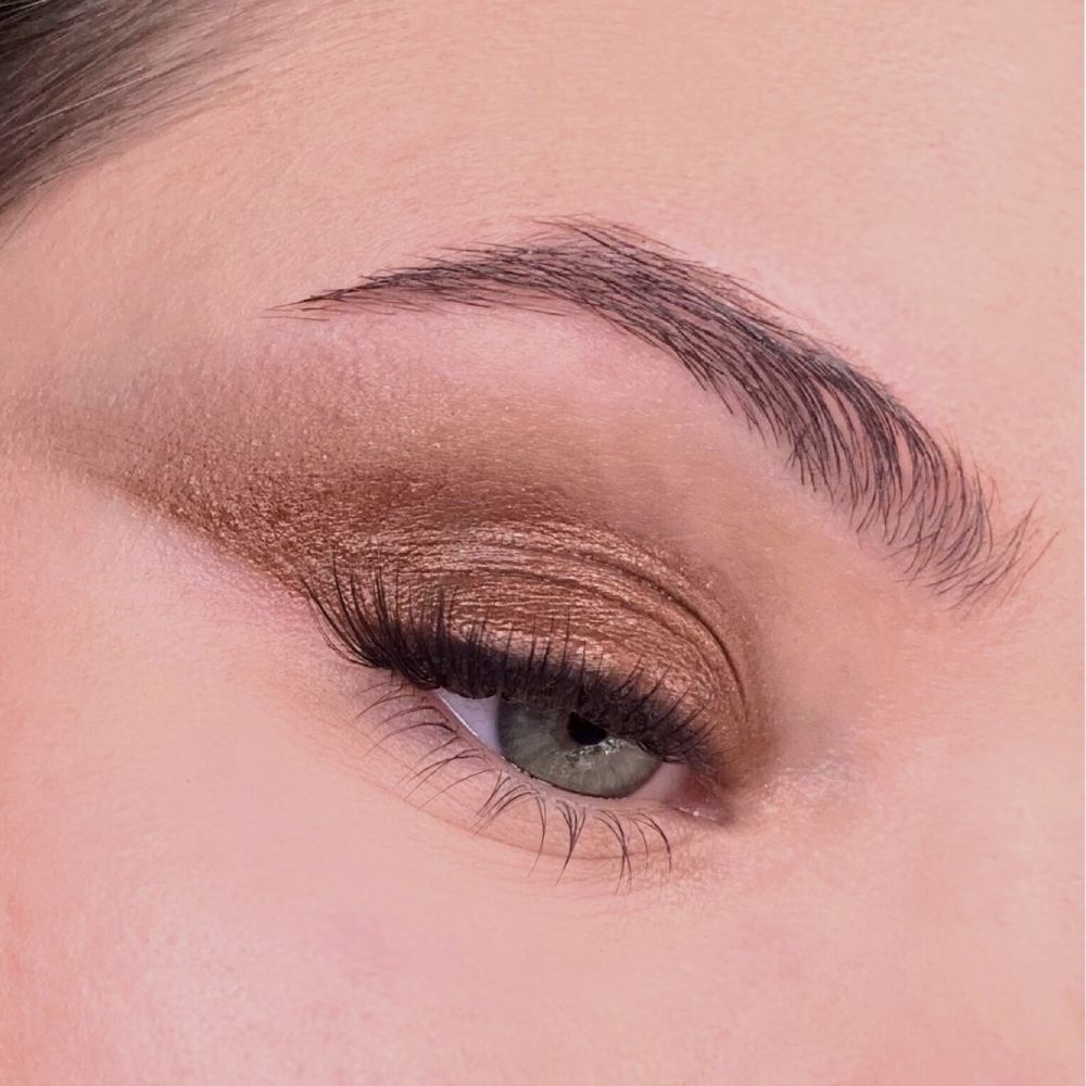 Occhio con ombretto marrone dorato. Ombretto sulla palpebra e come eyeliner. Sopracciglio marrone.