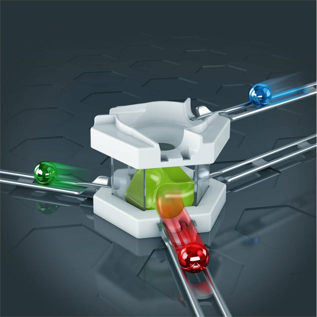 Mixer bianco con biglie colorate su binari. Biglie rosse, verdi, blu e arancioni. Sfondo grigio.