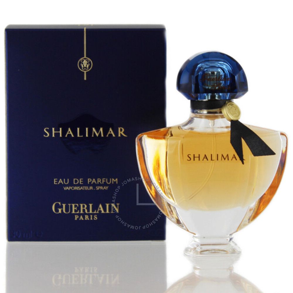 Guerlain Shalimar Eau de Parfum Spray. Flacone con tappo blu e fiocco nero. Confezione con logo e nome del prodotto.