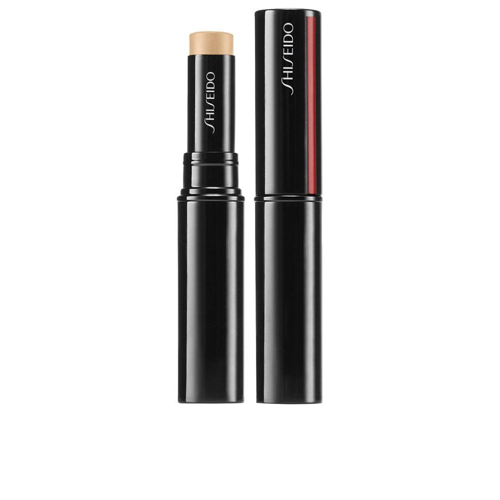 Correttore in stick nero con prodotto beige. Tappo accanto. Logo Shiseido su stick e tappo. Striscia rossa sul tappo.