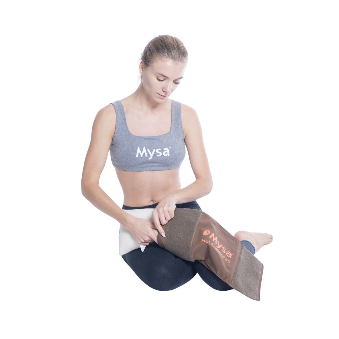 Donna seduta che tiene un cuscino marrone. Il cuscino ha il logo Mysa. Indossa abbigliamento sportivo.