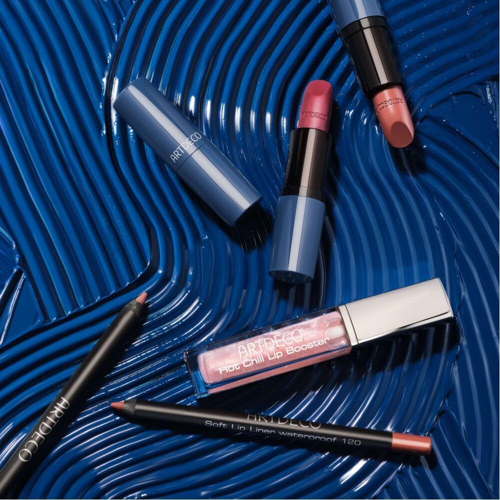 Prodotti cosmetici su sfondo blu. Artdeco Hot Chili Lip Booster, rossetti, matite labbra. Testo del prodotto visibile.