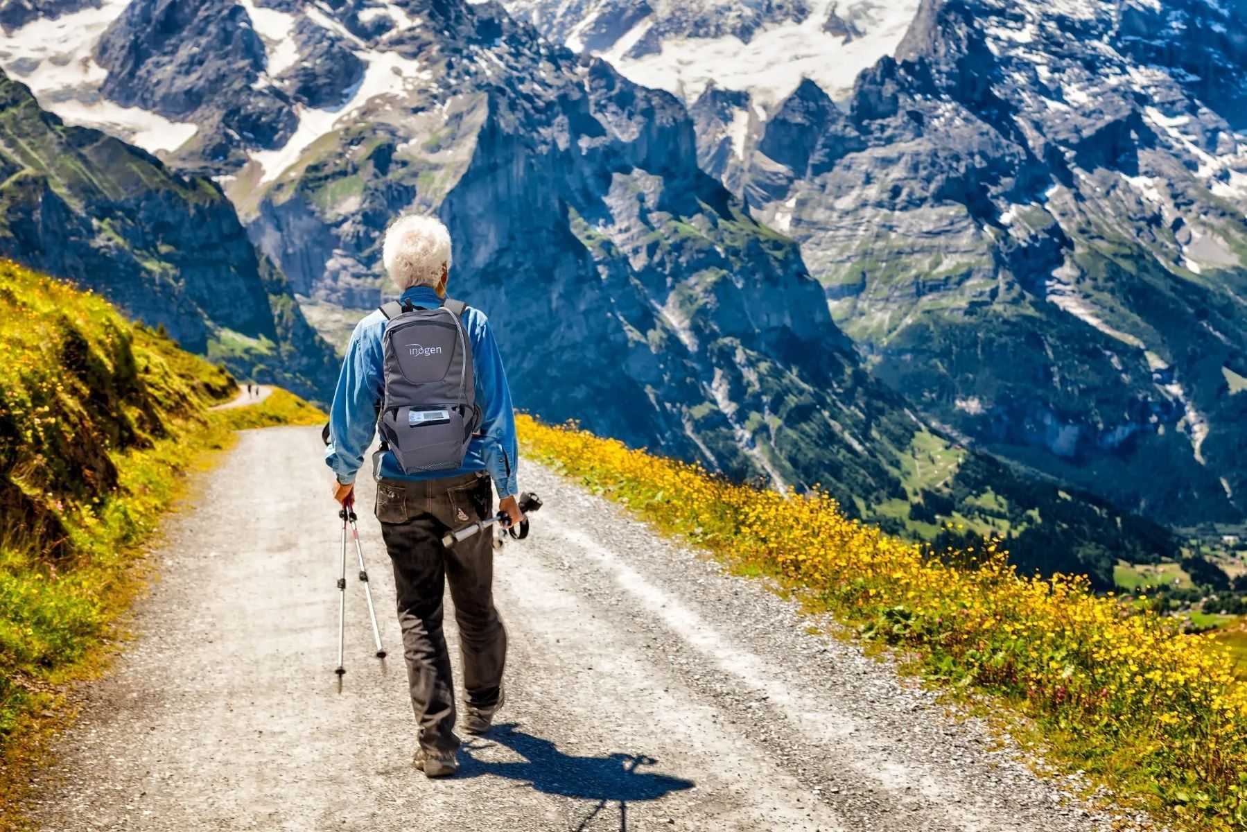 Escursionista con zaino e bastoncini su un sentiero di montagna.