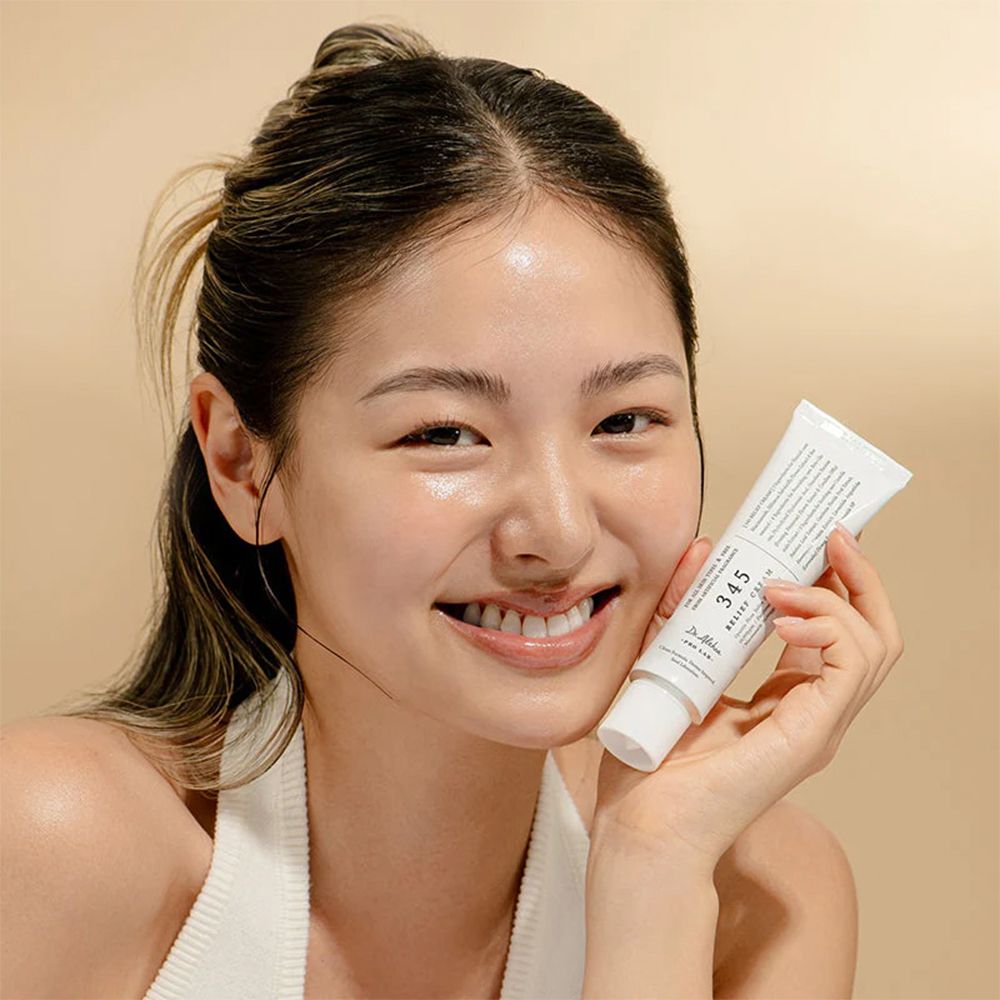 Una giovane donna tiene un tubetto bianco di Dr. Althea 345 Relief Cream.