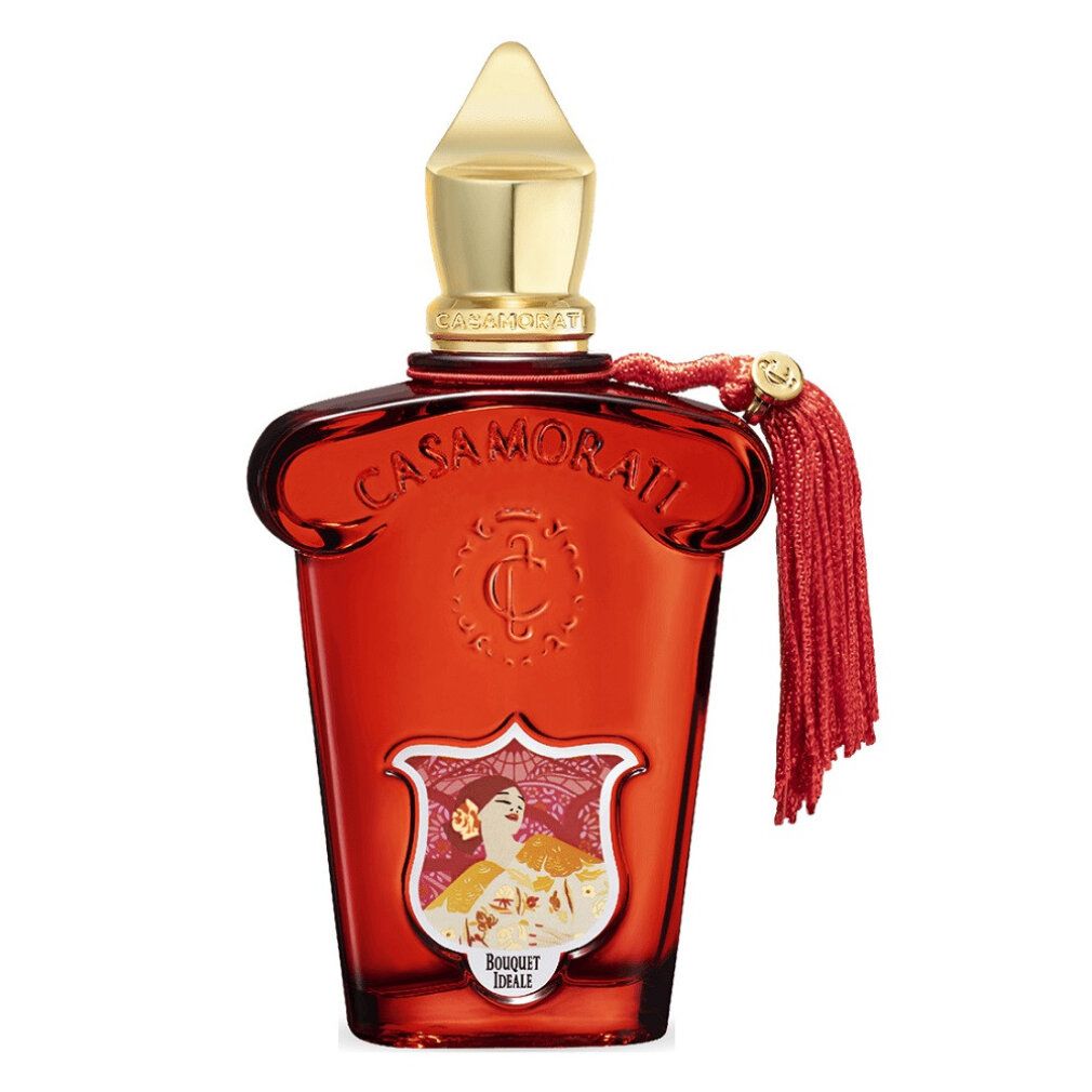 Flacone rosso con tappo dorato e nappa. Etichetta con motivo floreale e scritta.