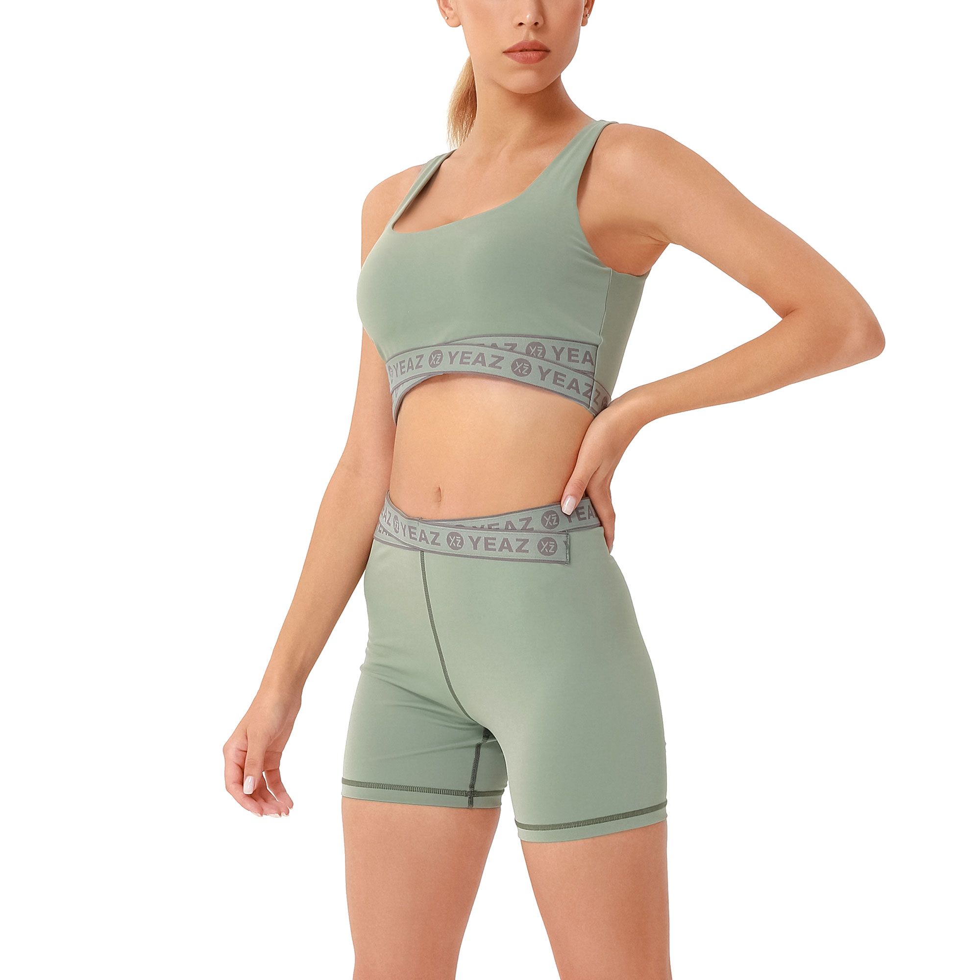 Reggiseno sportivo verde e pantaloncini da ciclista con fascia grigia del marchio.